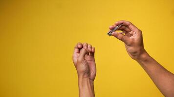 Man's hand holding nail clippers with both hands isolated in pink background photo