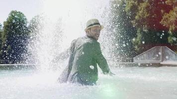 Lycklig ung man dans i vatten fontän i sommar tid video