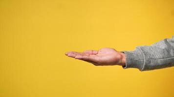 A man's hand shows a palm up gesture on a yellow orange background photo