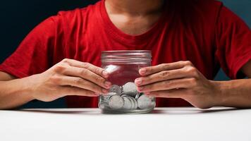 man with coins in a clear transparent glass jar. saving money concept photo