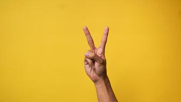 Man's hand pointing finger at camera on yellow background photo