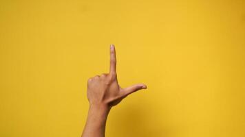 Man's hand with index finger up and thumb gesture on yellow background photo