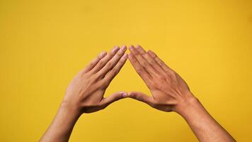 Men's hands make a triangle shape isolated on a yellow background photo