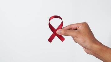 Hand holding red ribbon on white background. supporting world concern day photo