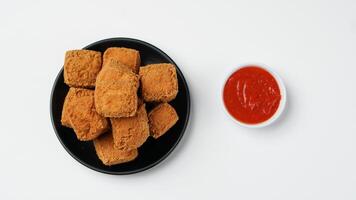 Fried tofu on a black plate with three sauces of mayonnaise, chili and sweet soy sauce on a white background photo