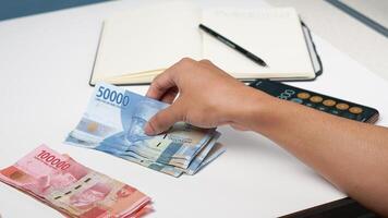 a man is counting Indonesian rupiah banknotes. financial management concept photo