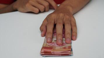 man's hand on Indonesian rupiah banknotes. financial management concept photo