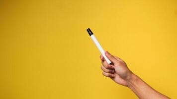 Man's hand holding a black marker on a yellow background photo
