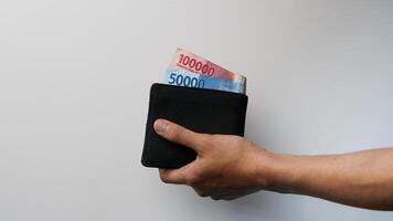 Man holding rupiah notes and wallet on white background photo