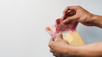 Hand holding rupiah money in a brown envelope. Indonesian currency photo