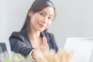 Selective focus of young Asian business woman showing thumbs up and looking at camera photo