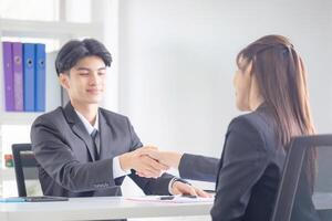 Business people shaking hands, Young man and woman shaking hands in the office photo