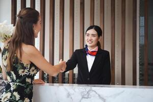 Receptionist and guest making handshake at hotel reception, Receptionist shaking hands with young female travelers at hotel counter photo