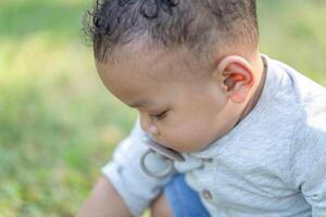 de cerca de linda pequeño niño chico jugando al aire libre en el jardín, niño chico en el parque foto