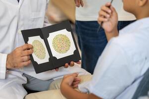 Optometrist doing color blindness disease perception test in optical shop, Boy doing eye test checking examination with optometrist in optics store photo