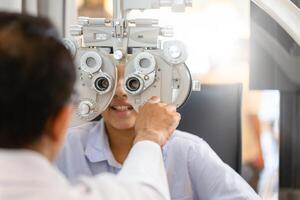 optometrista haciendo visión pruebas para niño paciente en clínica, indio niño elegir los anteojos en óptica almacenar, chico haciendo ojo prueba comprobación examen con optometrista en óptico tienda foto