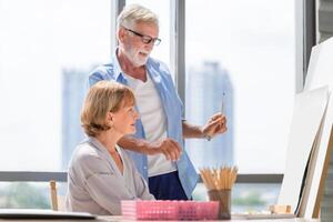 Portrait of happy senior couple painting on a canvas in living room, Older man and woman drawing together on a canvas, Happy retirement concepts photo