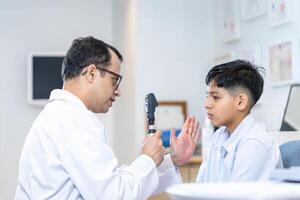 optometrista haciendo visión pruebas para niño paciente en clínica, indio niño elegir los anteojos en óptica almacenar, chico haciendo ojo prueba comprobación examen con optometrista en óptico tienda foto