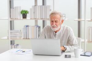 mayor hombre comprobación su facturas, maduro hombre en el vivo habitación con ordenador portátil foto