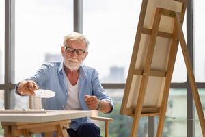 Senior man painting on canvas at home, Elderly man painting on a canvas, Happy retirement concepts photo