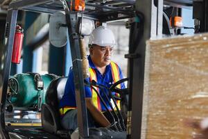 Worker driver at warehouse forklift loader works to containers box, worker man in warehouse with forklift photo