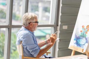 Senior man painting on canvas at home, Elderly man painting on a canvas, Happy retirement concepts photo
