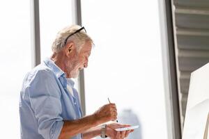 Senior man painting on canvas at home, Elderly man painting on a canvas, Happy retirement concepts photo