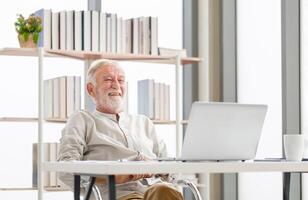 contento mayor hombre con ordenador portátil y café taza en mesa disfrutando en vivo habitación, maduro hombre en el vivo habitación con un ordenador portátil foto