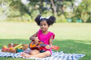 niño niña jugando guitarra al aire libre, bonito pequeño niño niña jugando el ukelele foto