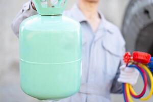 Car Air Conditioning Repair, Repairman holds bucket refrigerant and monitor tool to check and fix car air conditioner system, Technician checks car air conditioning system refrigerant recharge photo