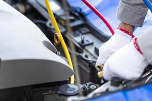 Technician man checks car air conditioning system refrigerant recharge, Repairman with monitor tool to check and fix car air conditioner system, Car Air Conditioning Repair photo