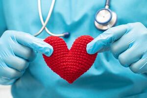 médico sosteniendo un corazón rojo en la sala del hospital, concepto médico fuerte y saludable. foto