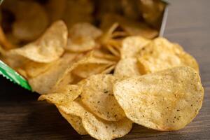 Potato chips, delicious spicy for crips, thin slice deep fried snack fast food in open bag. photo