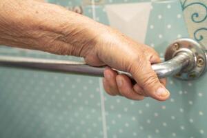 Asian senior woman patient use toilet bathroom handle security in nursing hospital, healthy strong medical concept. photo