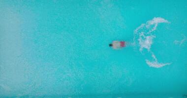 Top down view of a man in red shorts swims in the pool. Slow motion video