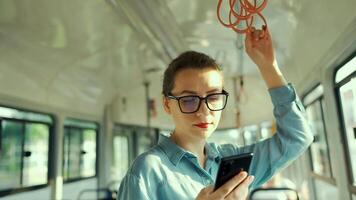 público transporte. mujer en lentes en tranvía utilizando teléfono inteligente lento movimiento video