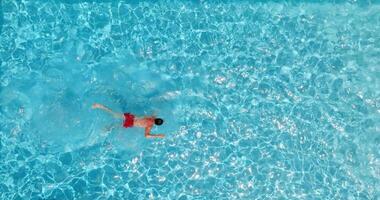 parte superior abajo ver de un hombre en rojo pantalones cortos nada en el piscina. lento movimiento video