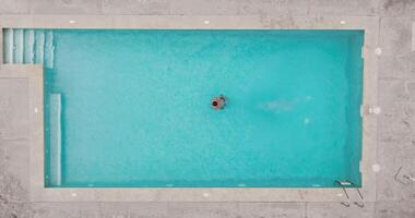 Top down view of a man in red shorts swims in the pool. Slow motion video