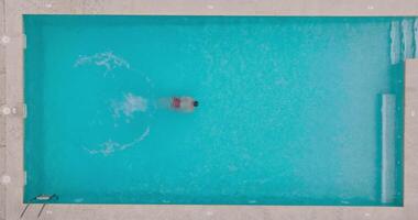 Top down view of a man in red shorts swims in the pool. Slow motion video