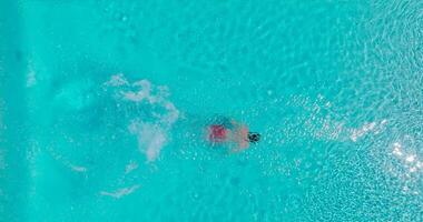 parte superior abajo ver de un hombre en rojo pantalones cortos nada en el piscina. lento movimiento video