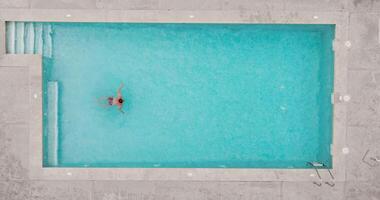 Top down view of a man in red shorts swims in the pool. Slow motion video
