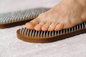 The man's feet are next to boards with nails. Yoga classes photo