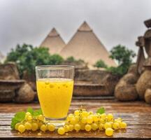 ai generado Fresco amarillo grosella jugo en un vaso en un de madera mesa con pirámide antecedentes foto