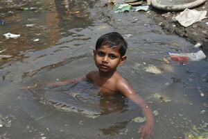 AI generated Poor Indian children bathe in the sewage water drain in the village photo
