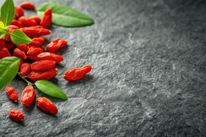 AI generated Fresh Goji berries on dark rough stone table. photo