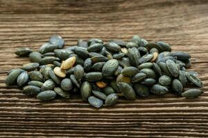 Pumpkin seeds seasoned using sea salt. Pumpkin seeds over wooden table. photo