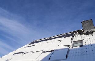 Solar panels producing clean energy on a roof of a residential house during winter. photo