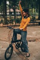 Happy young Asian woman while riding a bicycle in a city park. She smiled using the bicycle of transportation. Environmentally friendly concept. photo