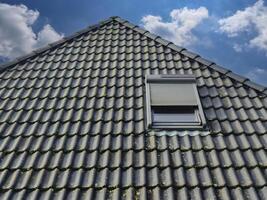 Open roof window in velux style with black roof tiles. photo