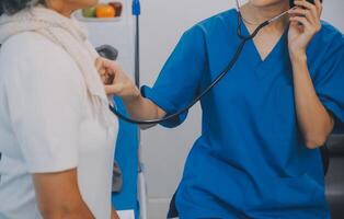 Close up of Female Doctor using stethoscope putting beat heart diagnose with patient in examination room at a hospital, check-up body, Medical and Health Care Concept. photo